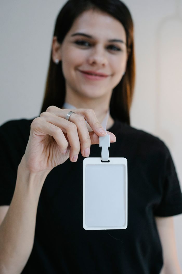 Happy young female smiling and looking at camera while demonstrating empty name tag during event